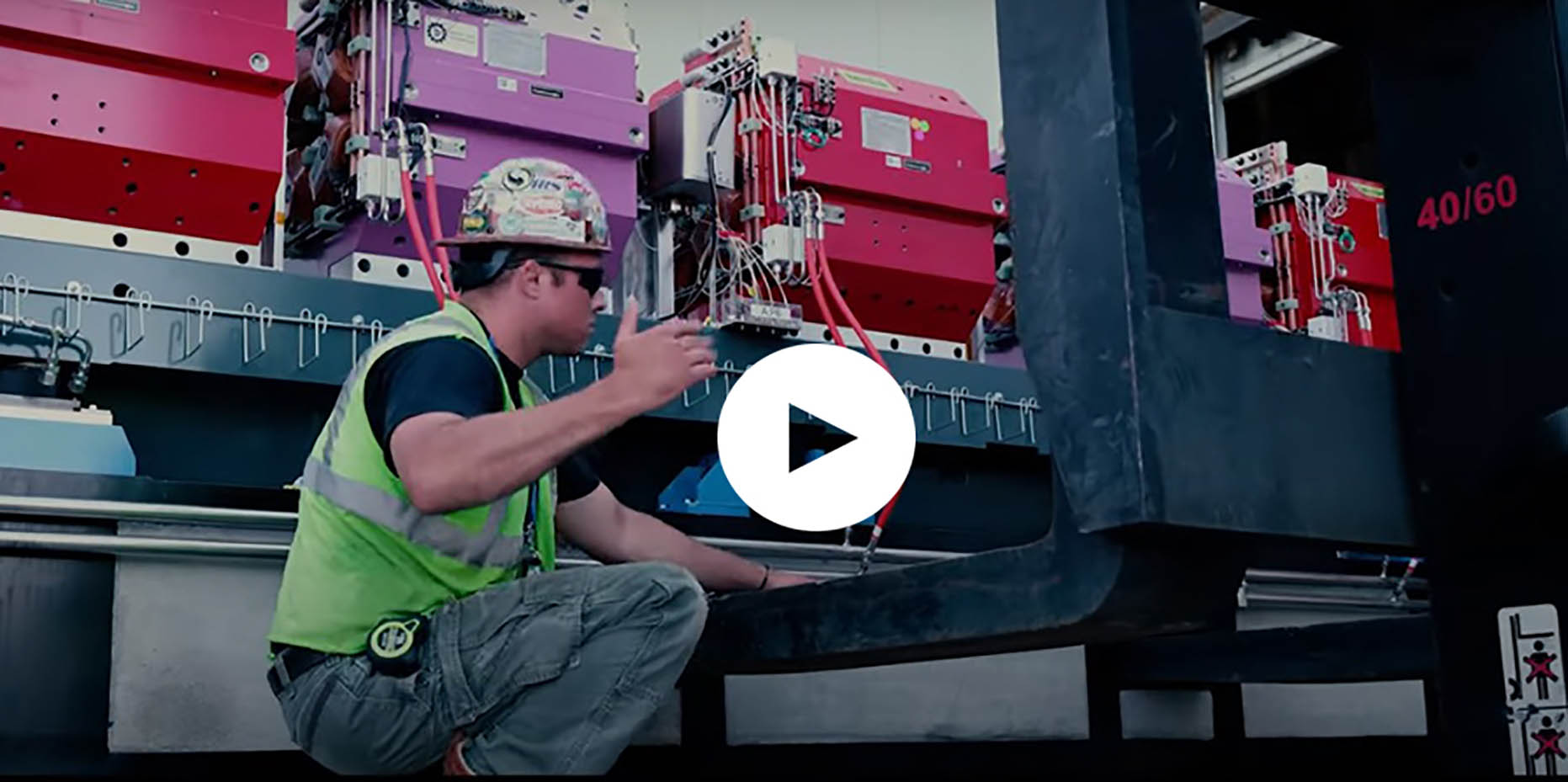 An APS Upgrade worker directs a forklift as it gently lowers a heavy module of colored magnets to the ground.