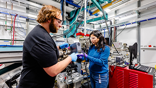 A pair of young scientists working on a machine.