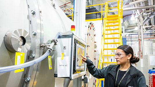 Woman wearing safety glasses checking a machine.