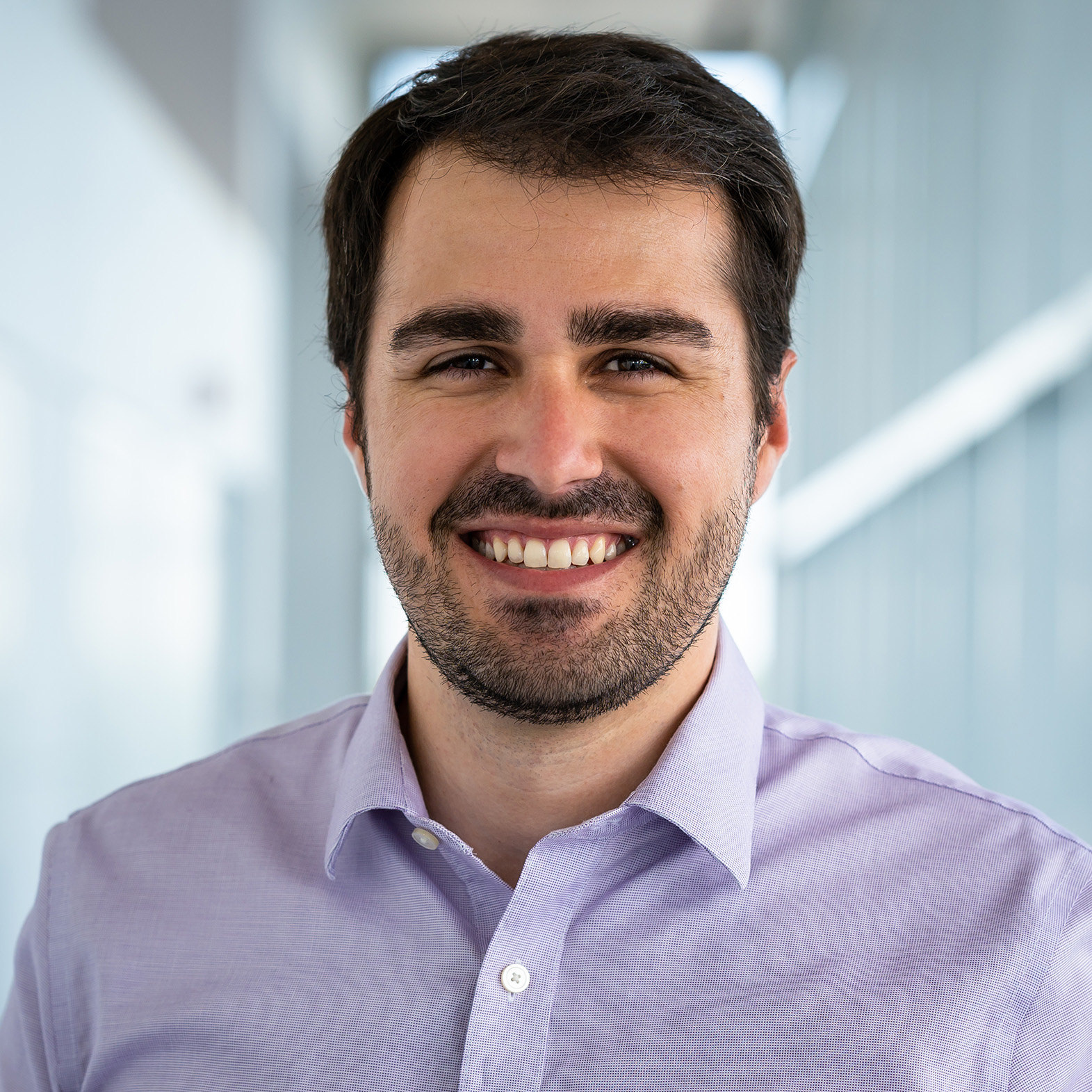 Headshot of a man with a beard smiling and wearing a collared shirt.