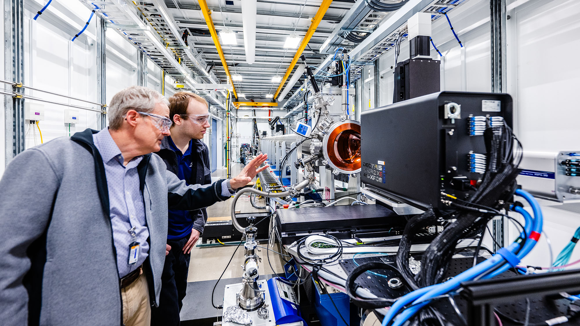 Two scientists next to a large scientific instrument.