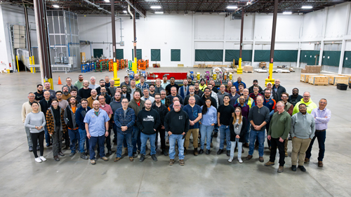 More than 100 people pose with a magnet in an empty storage space.