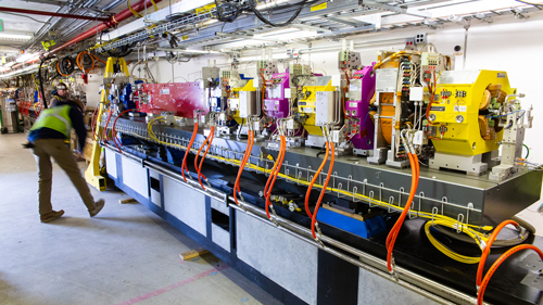 A worker aligns a large module of magnets into place in the APS storage ring tunnel.