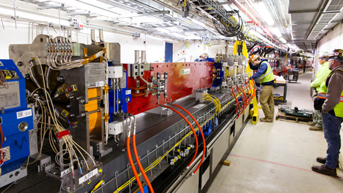 Workers complete the alignment of a large module of magnets in the APS storage ring tunnel.