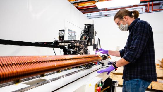 Argonne engineer Matt Kasa demonstrates the system that winds superconducting magnets for use in the APS. Each magnet uses three kilometers of precisely spaced wire to generate its magnetic field. (Image by Jason Creps, Argonne National Laboratory.) 