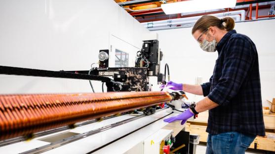 Argonne engineer Matt Kasa demonstrates the system that winds superconducting magnets for use in the APS. Each magnet uses three kilometers of precisely spaced wire to generate its magnetic field. (Image by Jason Creps, Argonne National Laboratory.)
